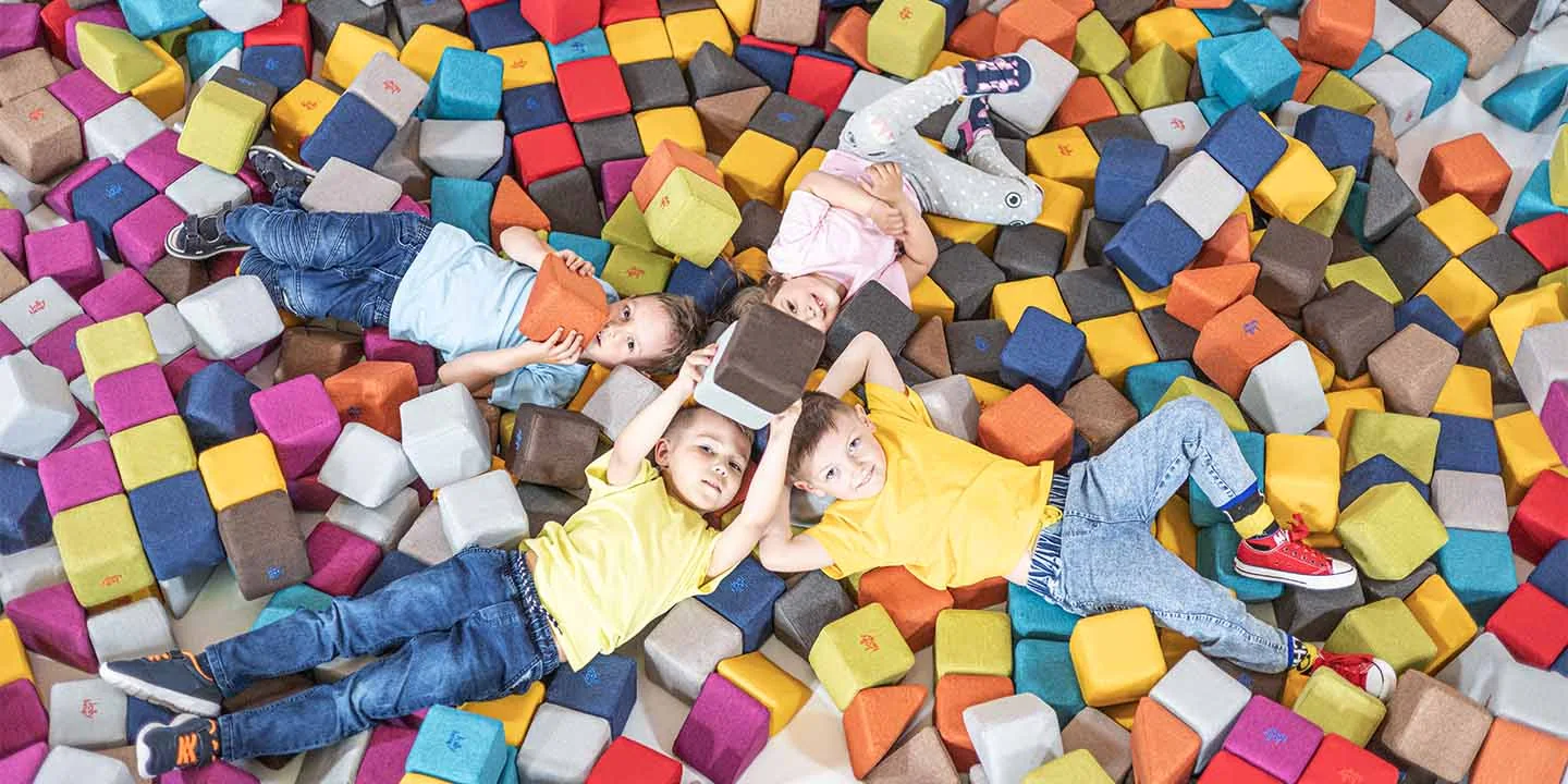 Kinder klettern auf weichen Bausteinen im Spielbereich